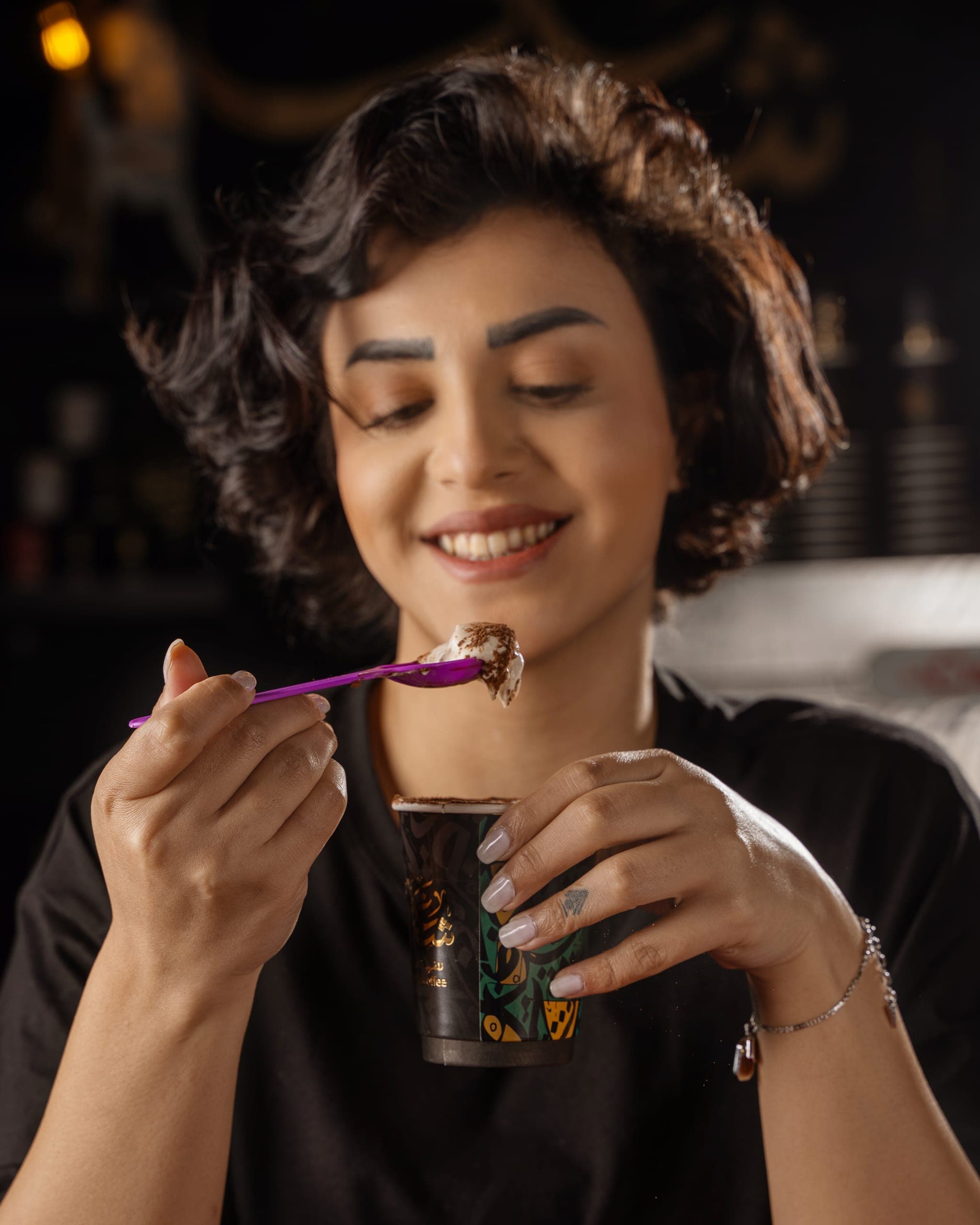 A guest smiling as she tastes dessert from a Shaghf cup